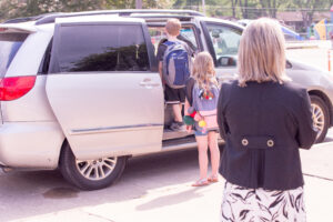 Elementary school dismissal with staff supervising carline pickup and verifying students are released to approved caregivers